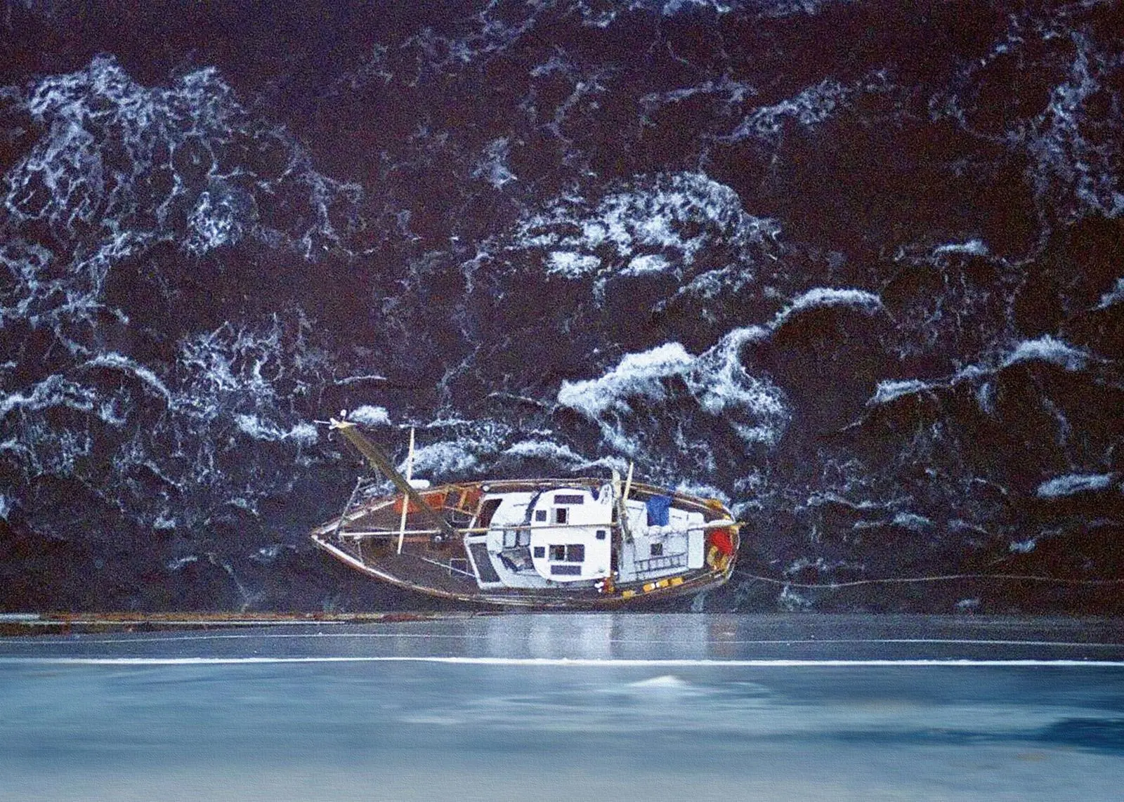 A small boat is dwarfed by the side of the ship attending its rescue